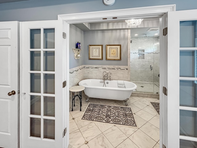 bathroom with a freestanding tub, a shower stall, marble finish floor, and tile walls
