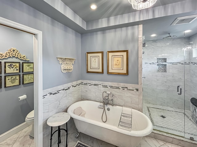 full bathroom featuring tile walls, a freestanding tub, toilet, a stall shower, and marble finish floor