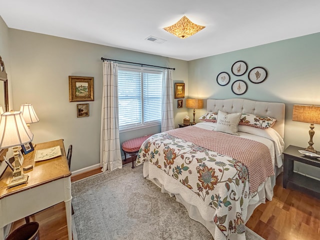 bedroom featuring baseboards, visible vents, and wood finished floors