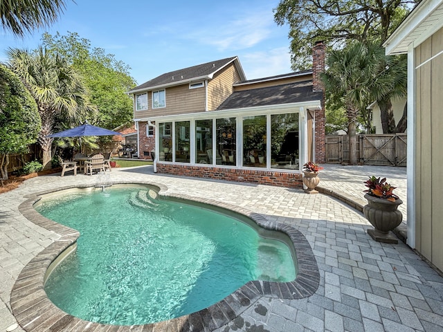 view of swimming pool featuring a sunroom, a fenced in pool, a fenced backyard, and a patio area