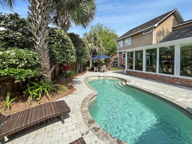 view of swimming pool with a sunroom, a fenced in pool, a fenced backyard, and a patio area
