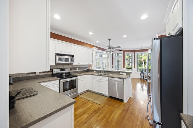 kitchen with white cabinets, sink, stainless steel appliances, and kitchen peninsula