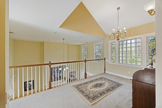 hallway with an inviting chandelier, vaulted ceiling, and carpet floors