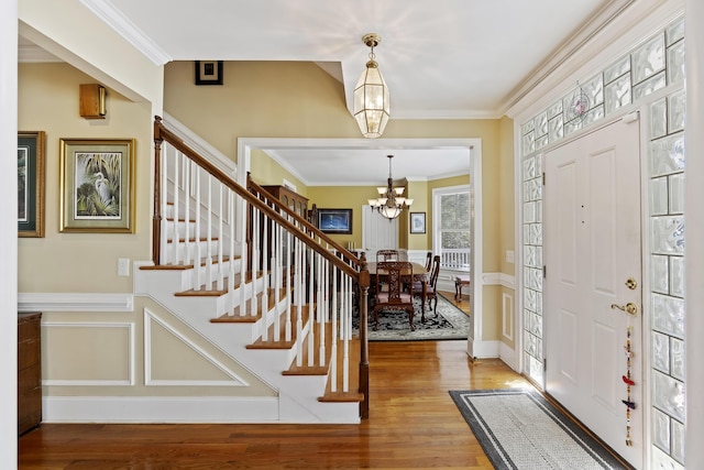 entryway with an inviting chandelier, hardwood / wood-style flooring, and ornamental molding