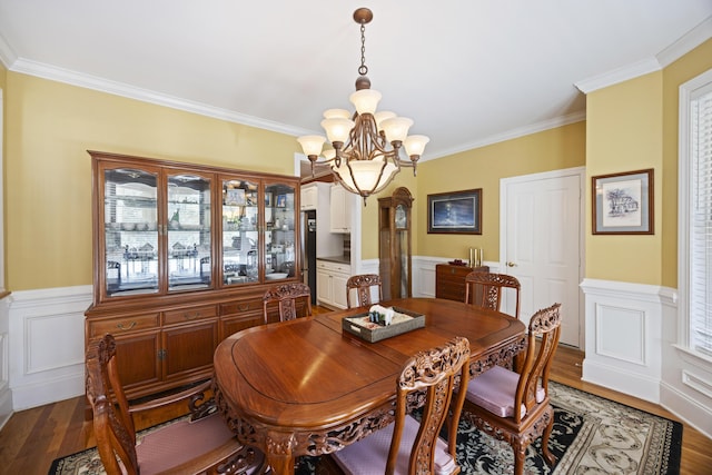 dining area with hardwood / wood-style floors, an inviting chandelier, and crown molding