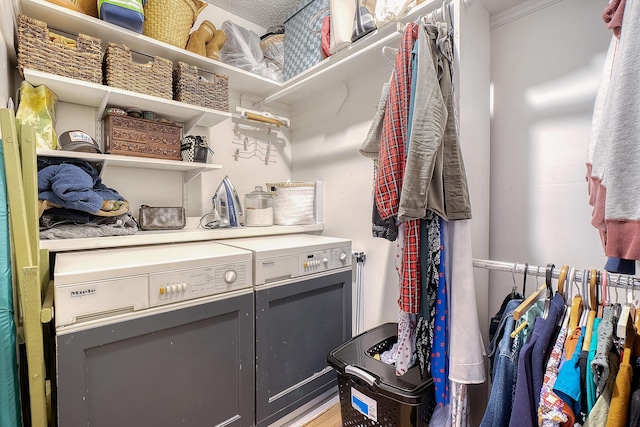 laundry room with crown molding, washer and clothes dryer, and wood-type flooring