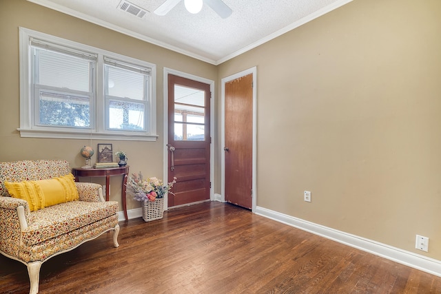 living area with ceiling fan, ornamental molding, a textured ceiling, and dark wood-type flooring