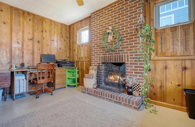 home office with wooden walls, ornamental molding, and a brick fireplace