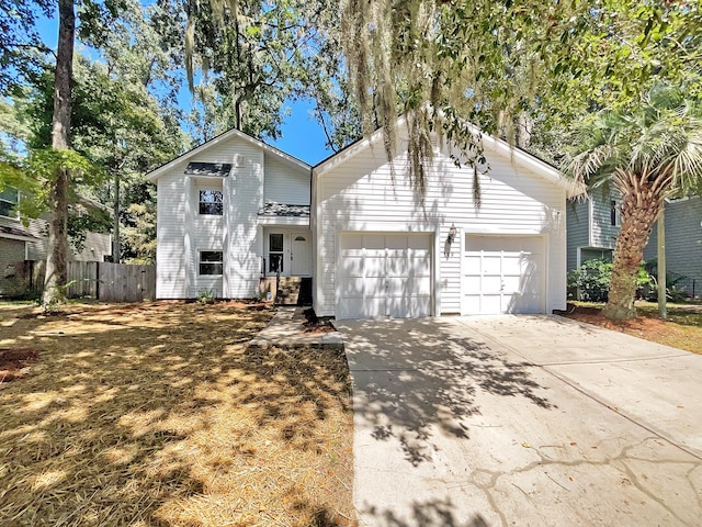 view of front facade with a garage, driveway, and fence