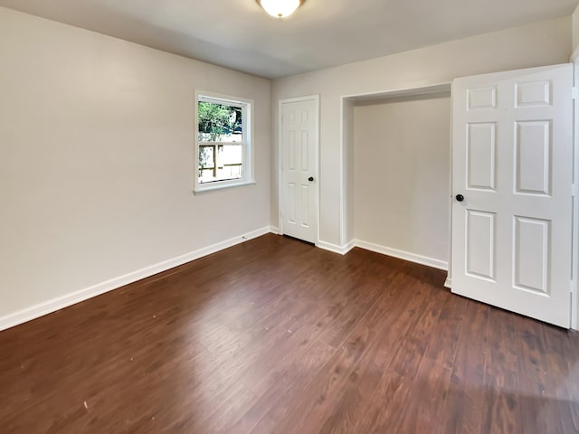 unfurnished bedroom with dark hardwood / wood-style flooring and a closet