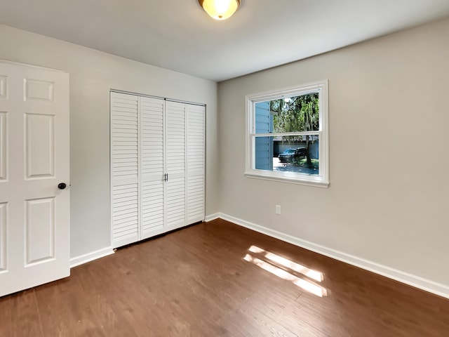 unfurnished bedroom with dark wood-type flooring and a closet