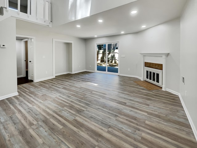 unfurnished living room featuring light wood-type flooring and a towering ceiling