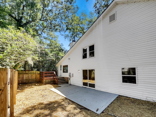 back of property with a wooden deck and a patio area