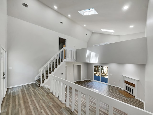 interior space with high vaulted ceiling, hardwood / wood-style flooring, and a skylight