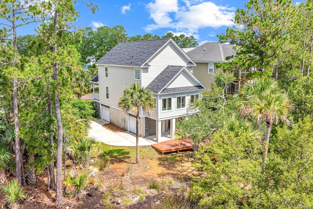 2301 N Creek Dr, Mount Pleasant, SC 29466 - rear view of property featuring a garage, a shingled roof, concrete driveway, a wooden deck, and view of scattered trees