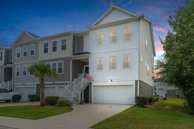 view of front facade featuring a lawn, driveway, stairs, and a garage