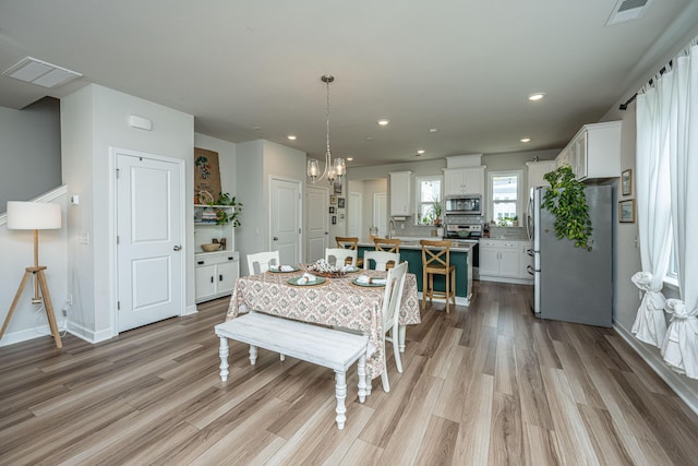 dining area featuring light wood-type flooring, visible vents, an inviting chandelier, and recessed lighting