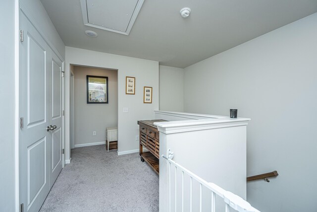 hall with attic access, carpet flooring, an upstairs landing, and baseboards