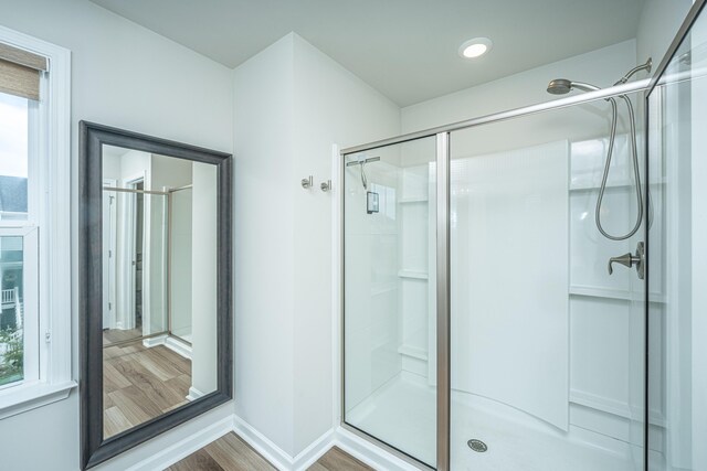 full bathroom with wood finished floors, a stall shower, and baseboards