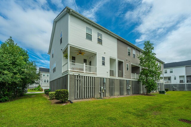 back of property featuring a balcony, a lawn, and ceiling fan