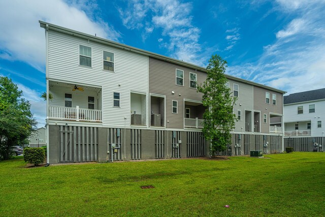 back of property featuring a balcony, ceiling fan, and a yard