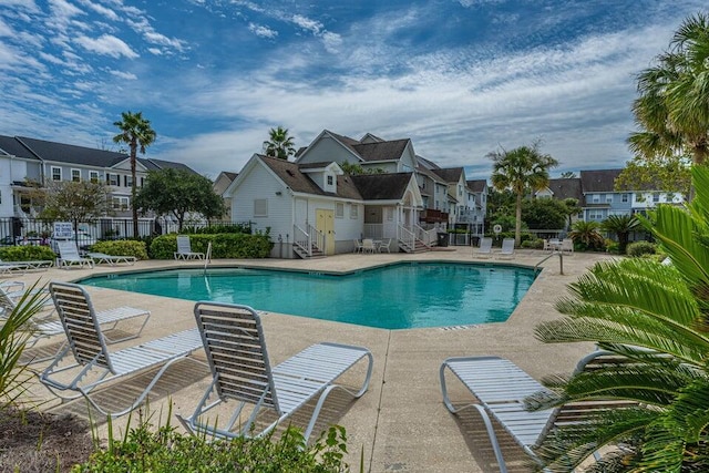 community pool with a patio area, a residential view, and fence