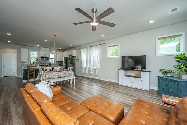 living area featuring visible vents, baseboards, recessed lighting, ceiling fan with notable chandelier, and wood finished floors