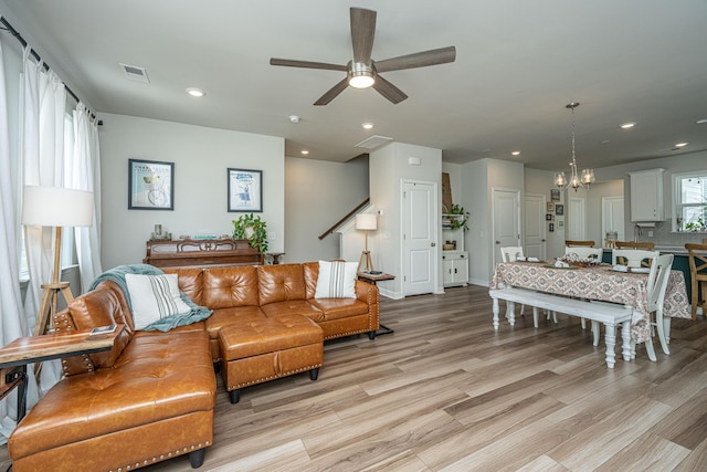 living room featuring visible vents, baseboards, light wood-type flooring, recessed lighting, and ceiling fan with notable chandelier