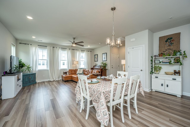 dining space with recessed lighting, light wood-style flooring, ceiling fan with notable chandelier, and baseboards