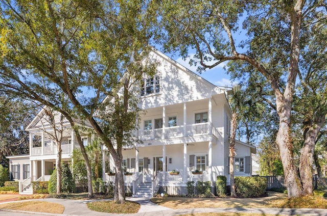 neoclassical home featuring a porch, fence, and a balcony