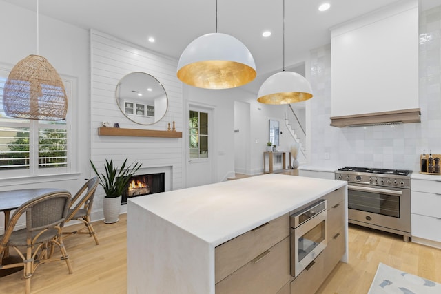 kitchen featuring white cabinets, a kitchen island, appliances with stainless steel finishes, light countertops, and pendant lighting