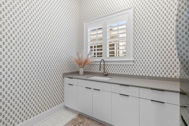 interior details with baseboards, a sink, and wallpapered walls