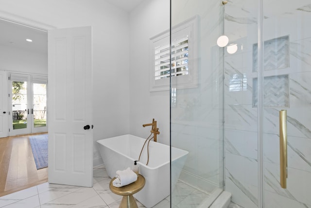 full bathroom with marble finish floor, a freestanding tub, and recessed lighting