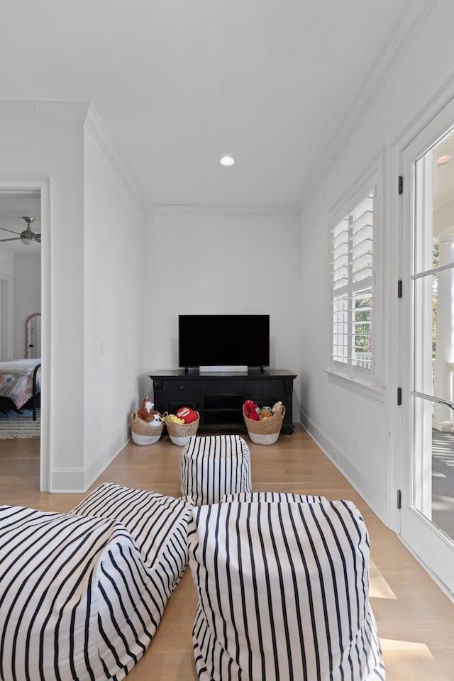 living room with light wood finished floors, ornamental molding, and baseboards