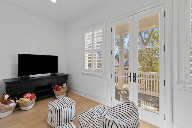 interior space featuring light wood-style floors, french doors, crown molding, and baseboards