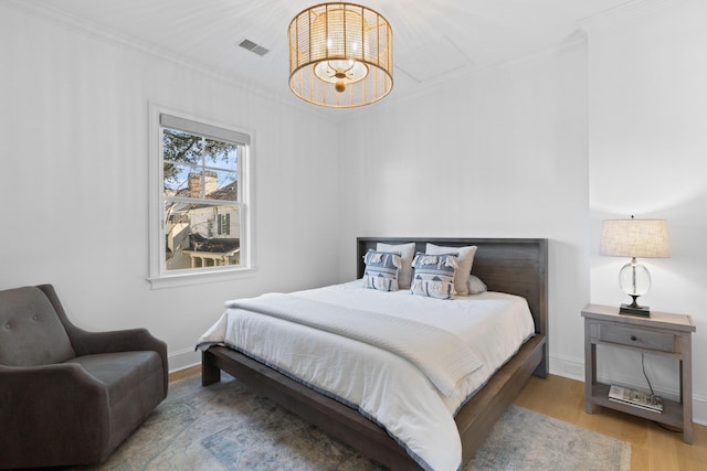 bedroom featuring ornamental molding, visible vents, light wood-style flooring, and baseboards