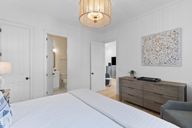 bedroom featuring ornamental molding, an inviting chandelier, ensuite bath, and light wood-style floors