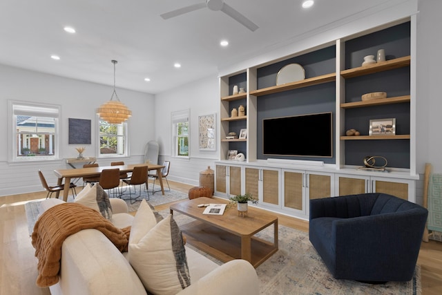 living area with built in shelves, recessed lighting, a wainscoted wall, and light wood-style floors