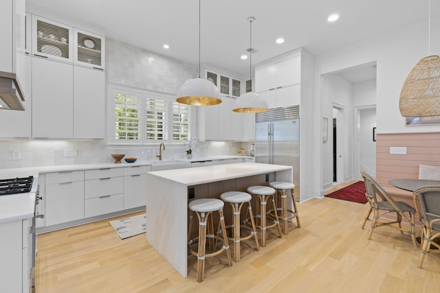 kitchen featuring decorative light fixtures, white cabinets, light countertops, and a center island