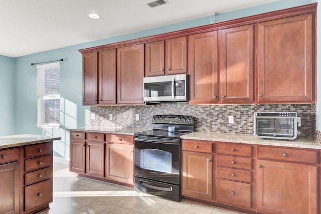 kitchen with tasteful backsplash, stainless steel microwave, light stone countertops, and black electric range