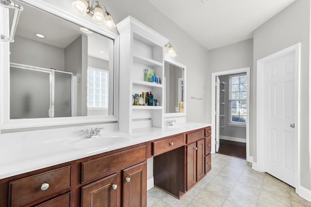 bathroom featuring double vanity, baseboards, a shower stall, and a sink