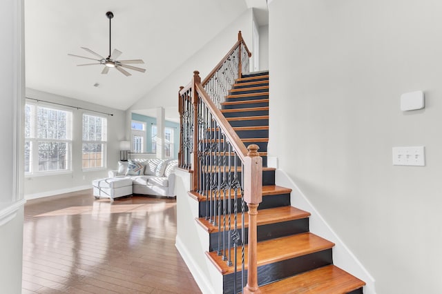 staircase featuring ceiling fan, hardwood / wood-style flooring, baseboards, and vaulted ceiling