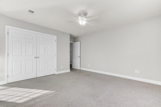 unfurnished bedroom featuring visible vents, a closet, carpet, baseboards, and ceiling fan