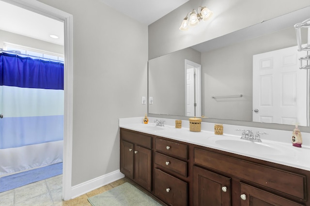 full bathroom featuring double vanity, a shower with curtain, baseboards, and a sink