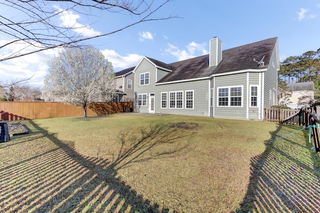 rear view of property featuring a yard, a fenced backyard, and a chimney