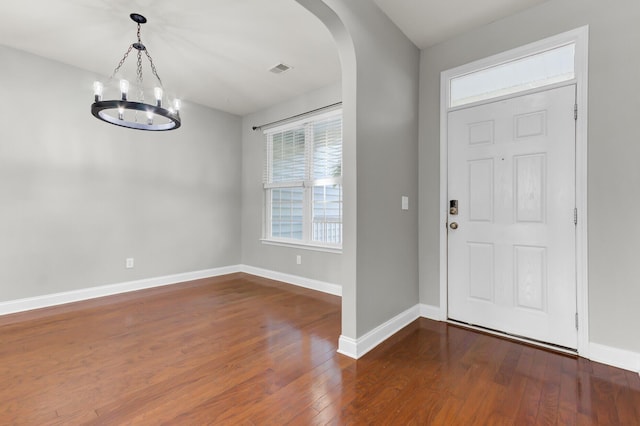 entrance foyer featuring baseboards, arched walkways, visible vents, and hardwood / wood-style flooring