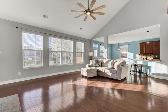 living area with visible vents, baseboards, dark wood-type flooring, and a ceiling fan