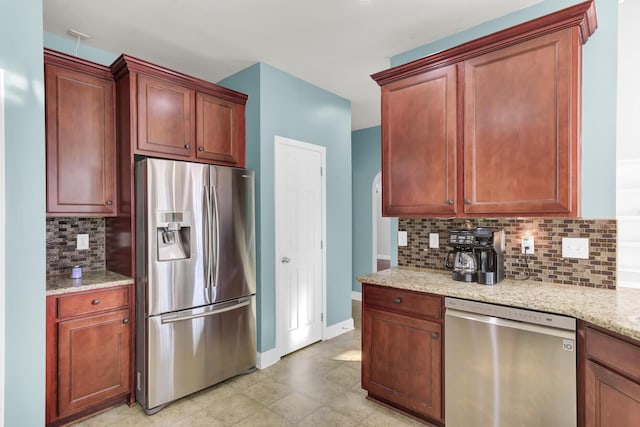 kitchen with decorative backsplash, light stone counters, baseboards, and stainless steel appliances