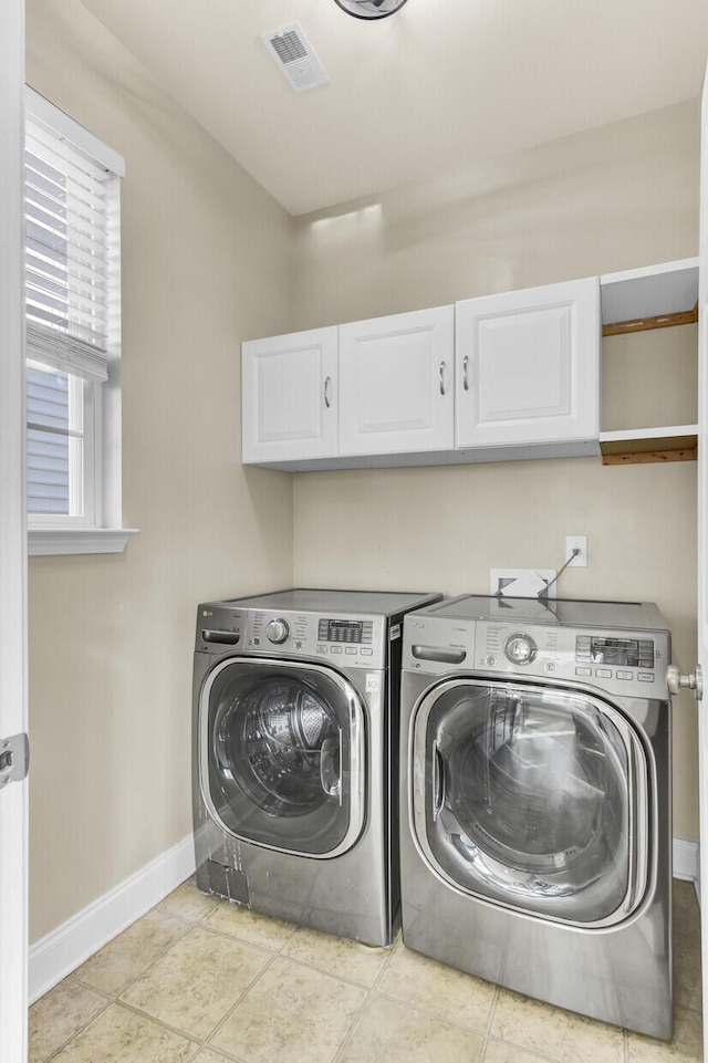 clothes washing area with tile patterned floors, visible vents, cabinet space, separate washer and dryer, and baseboards