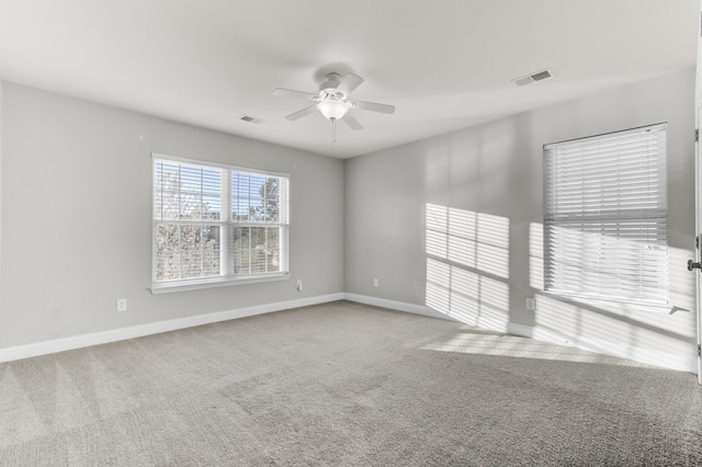 empty room with visible vents, baseboards, carpet, and a ceiling fan